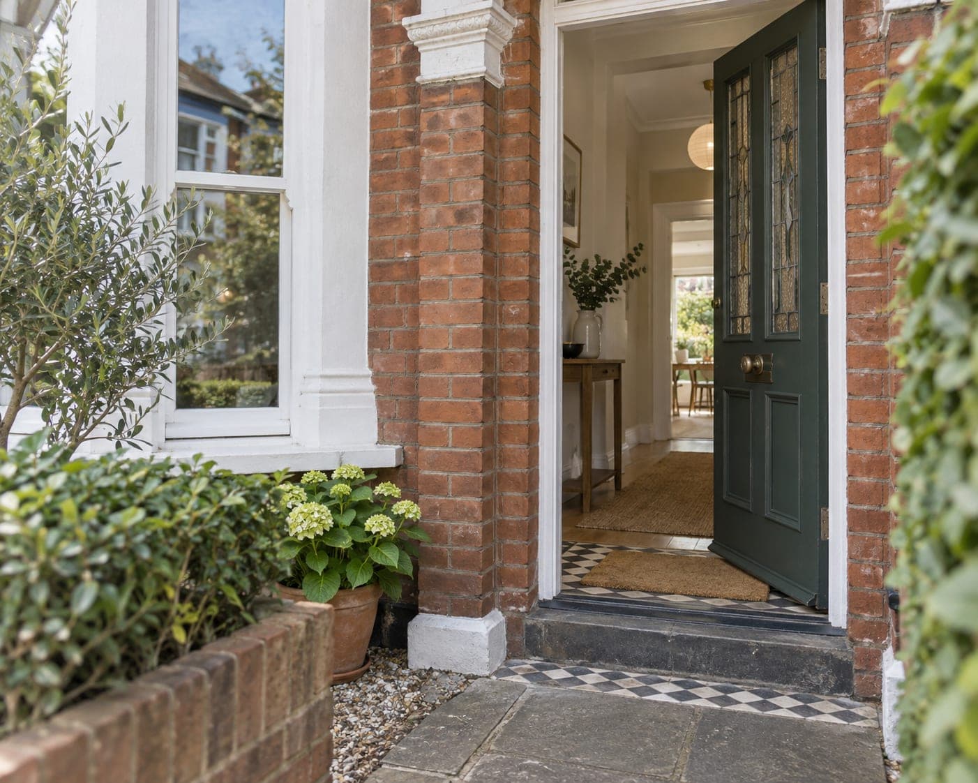 The open front door of a period house, looking through to a bright hallway